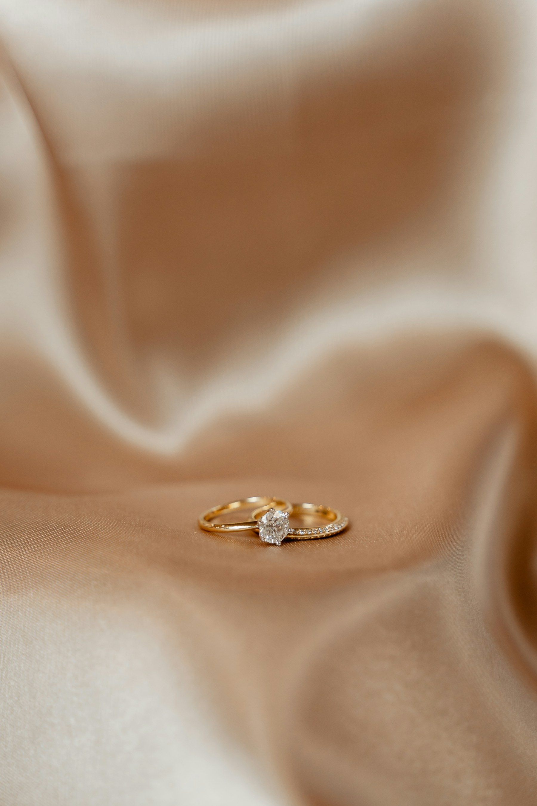 A solitaire diamond ring resting on softly folded silk